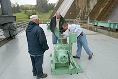 Robert Nieto, left, Jerry Pretzer and John Williams take part in opening the four 96-inch valves the Bureau of Reclamation operates at Friant Dam to release water into the San Joaquin River. Weather predictions and limited storage capacity in the river drainage system prompted an increase Monday in the water released.